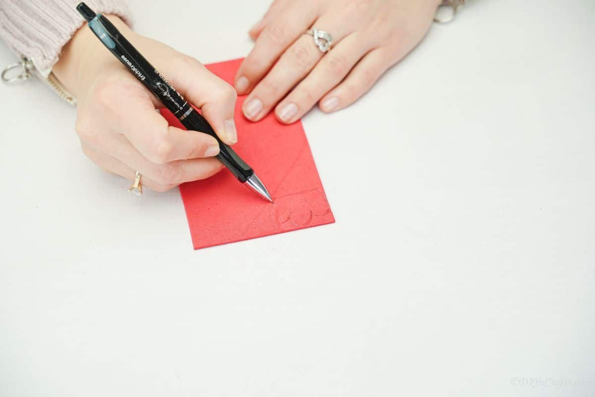 hand holding black pen against red foam paper
