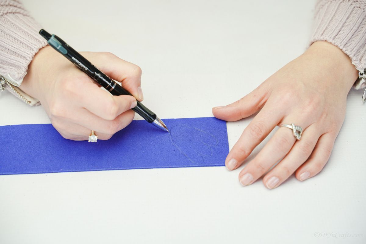 hand drawing foot shape onto blue foam paper on white table