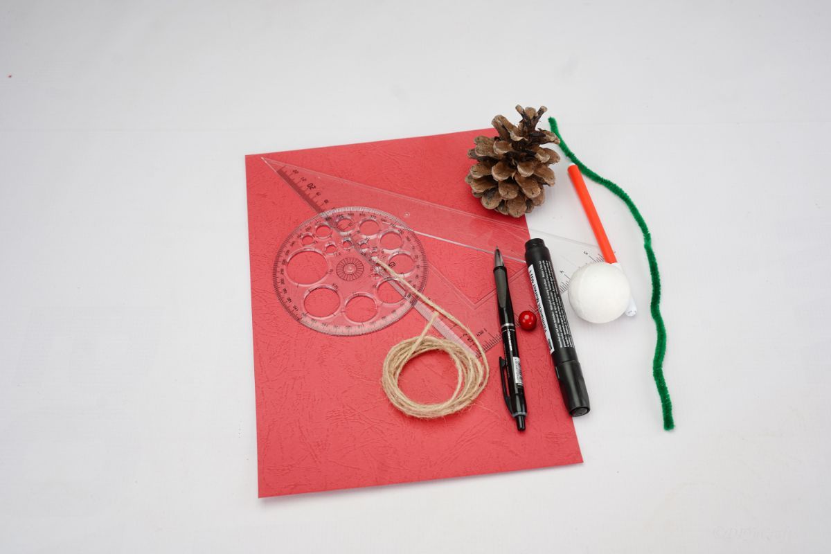 red paper pinecone pipe cleaner and twine on white table