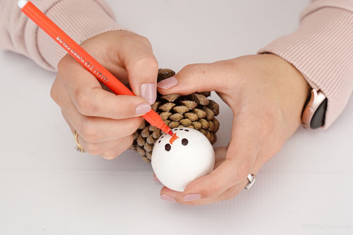 orange marker making nose on white ball for ornament