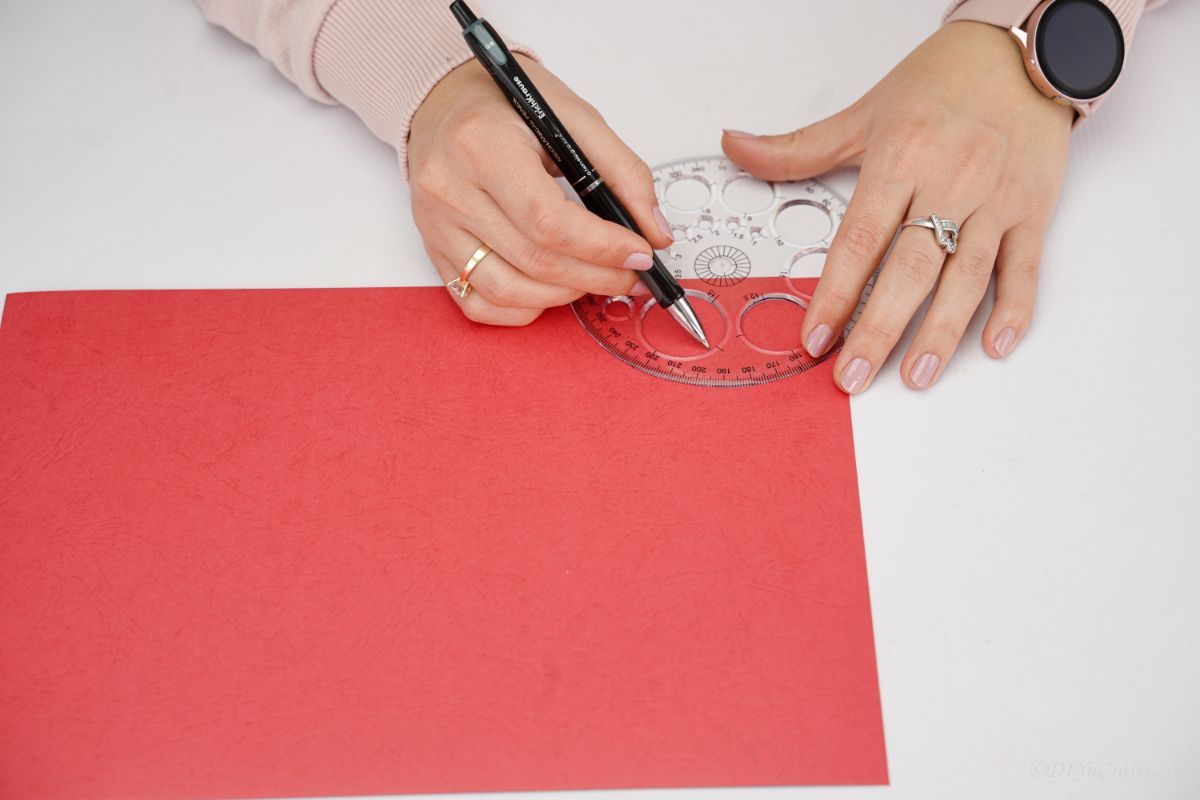 hand tracing circle on red paper