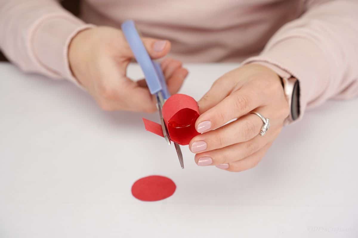 blue scissors trimming edge of red paper