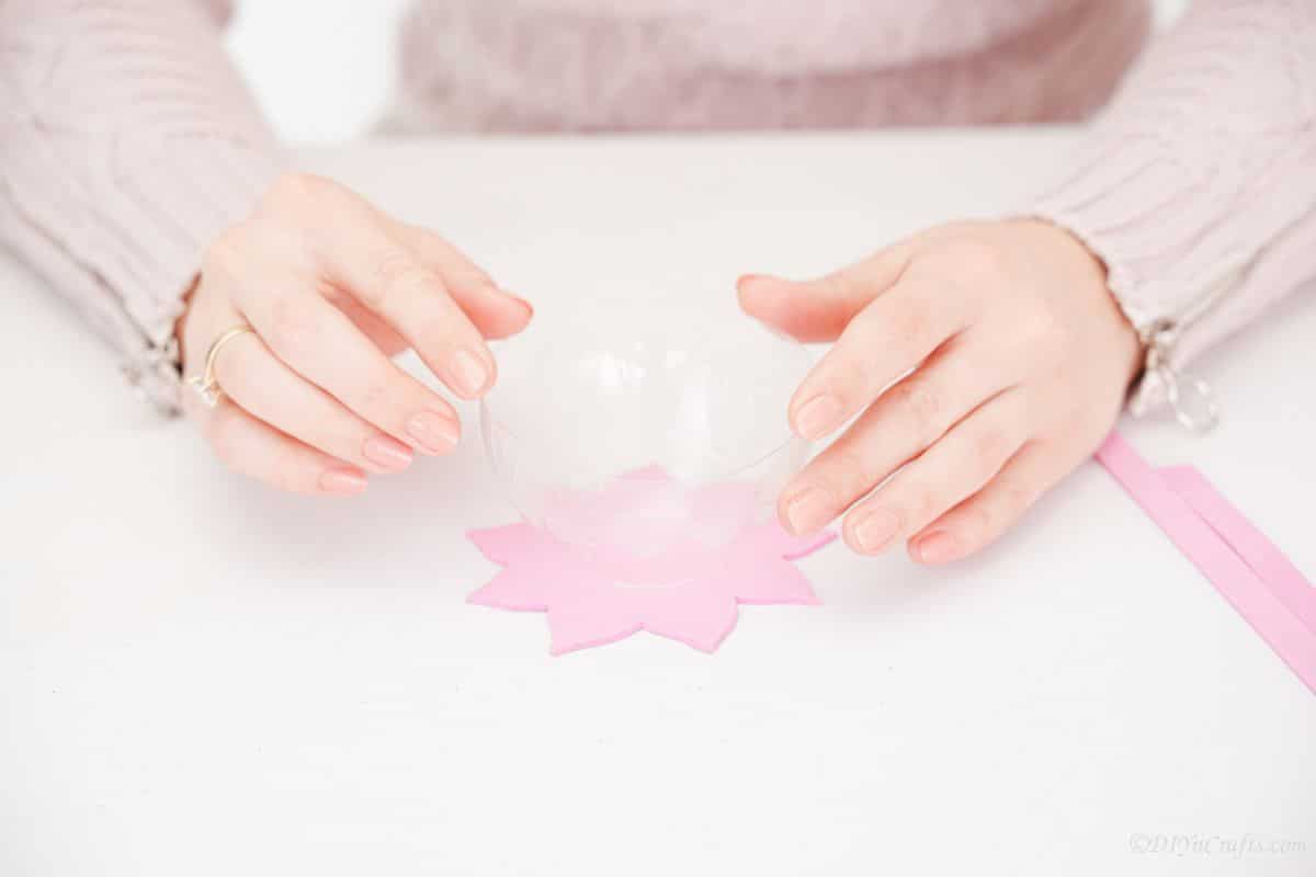 Hand putting clear bottle cup on top of pink flower foam piece