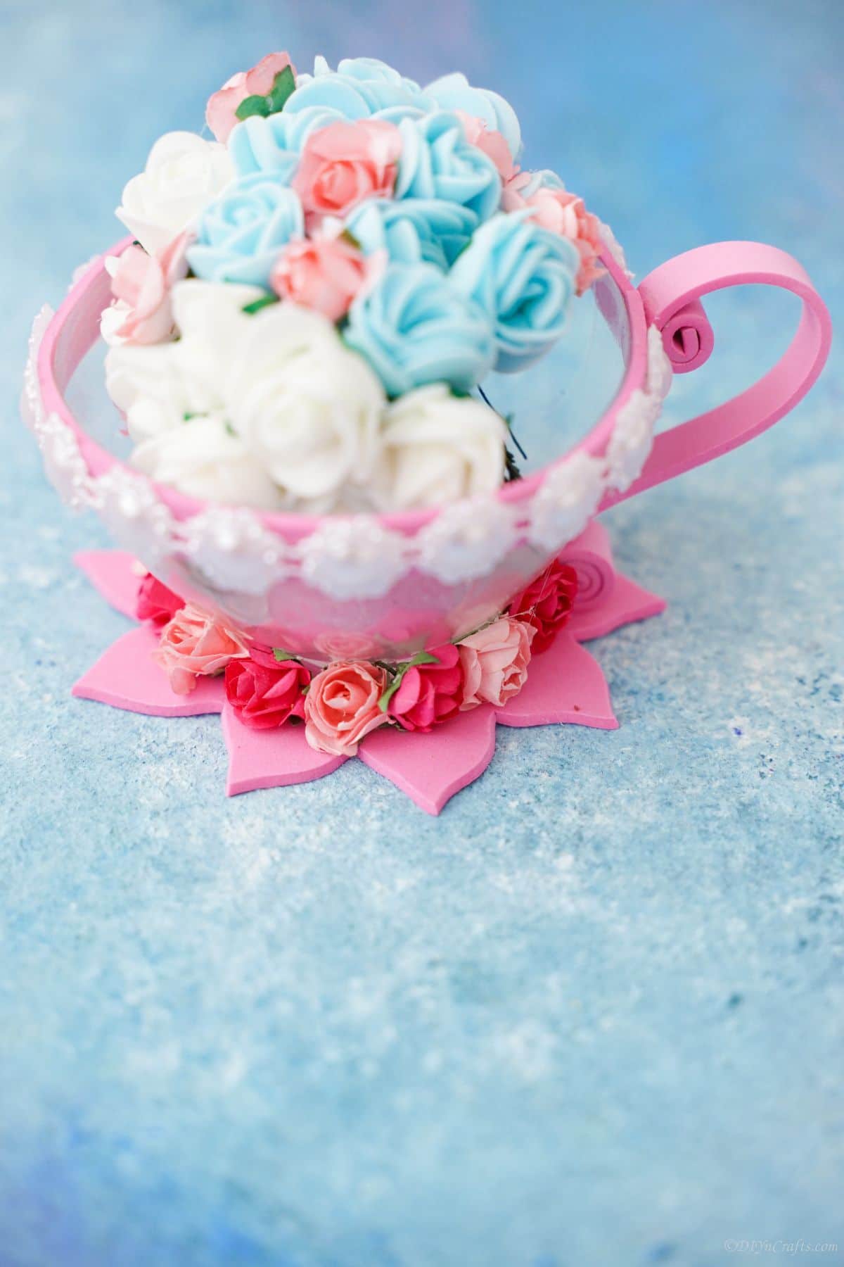 light blue paper under pink and white teacup holding blue and white mini roses