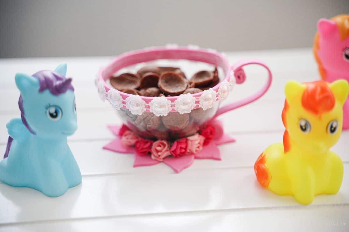 pink and white plastic bottle cup on white table with horse figurines