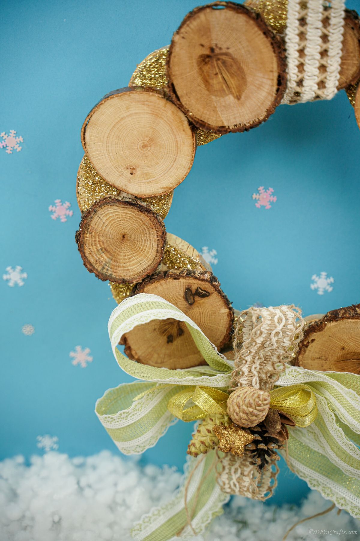 sideo f wreath with wood slice and green bow on blue background