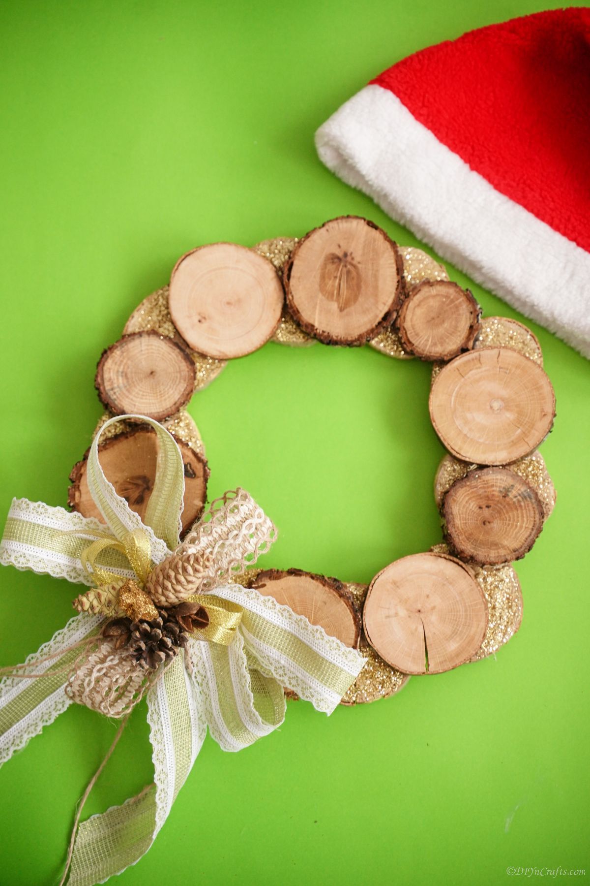 bright green background behind wood slice wreath with santa hat in corner