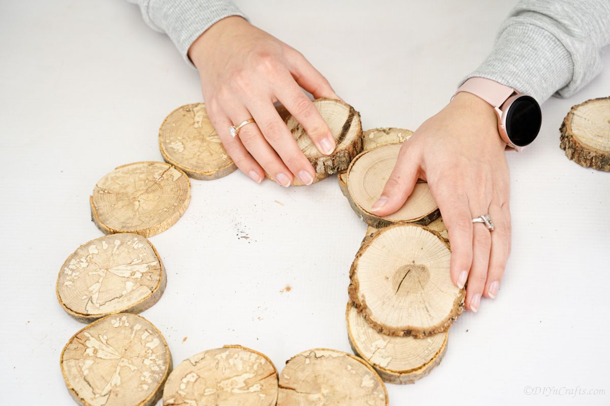 gluing wood slices on top of wreath circle