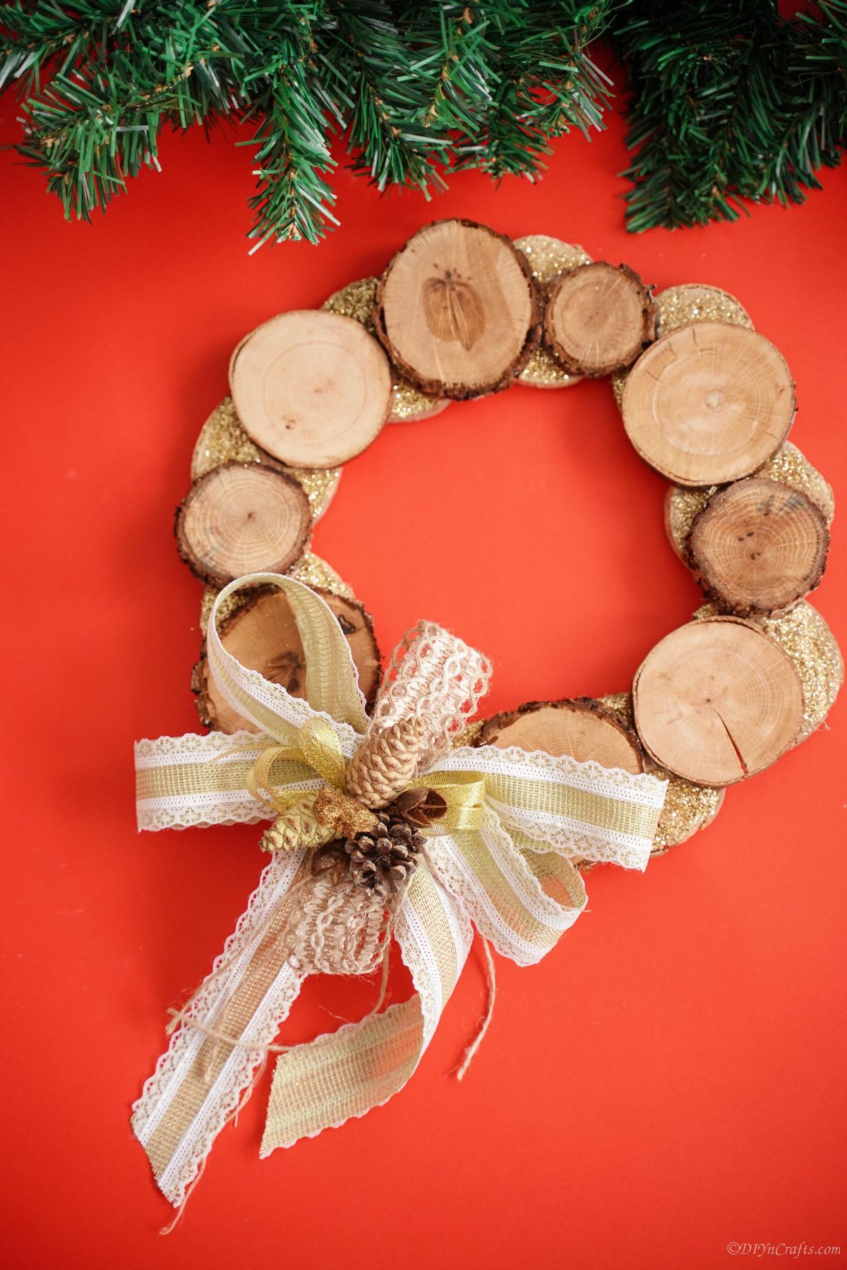 red background with greenery above wood slice wreath
