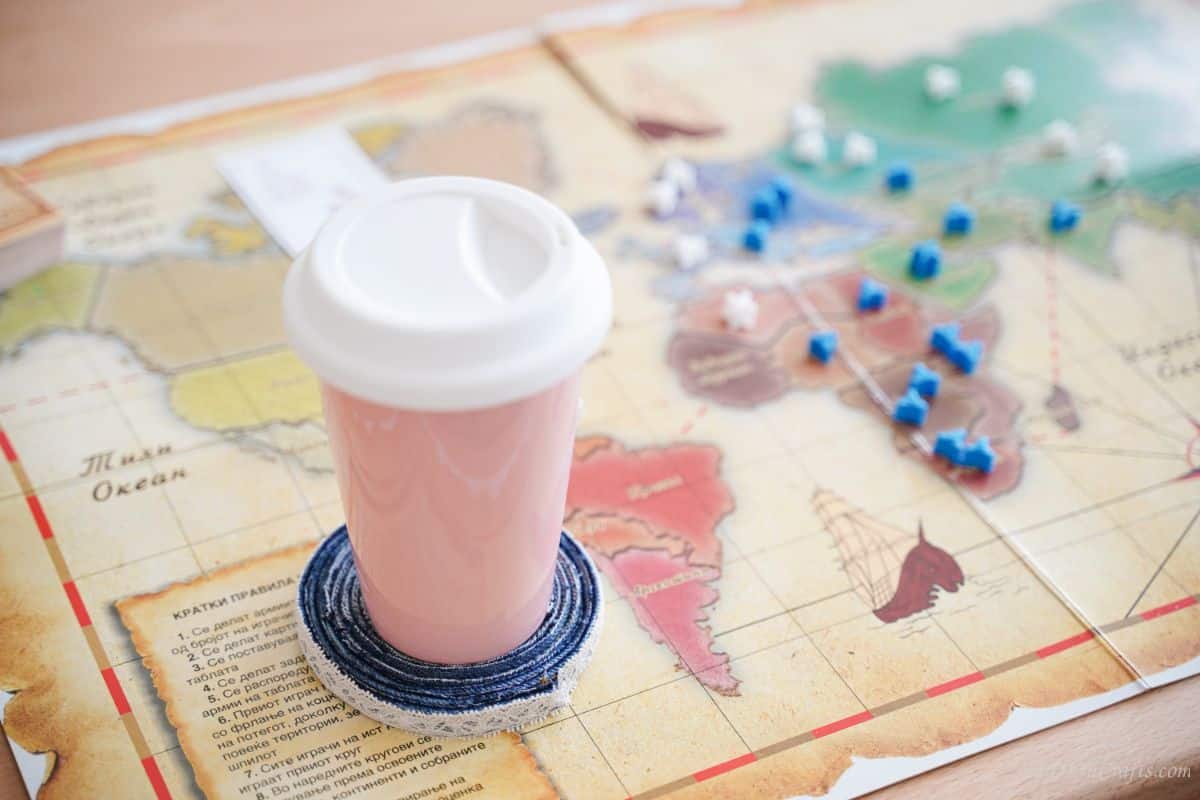 pink cup with white lid on top of denim coaster on map