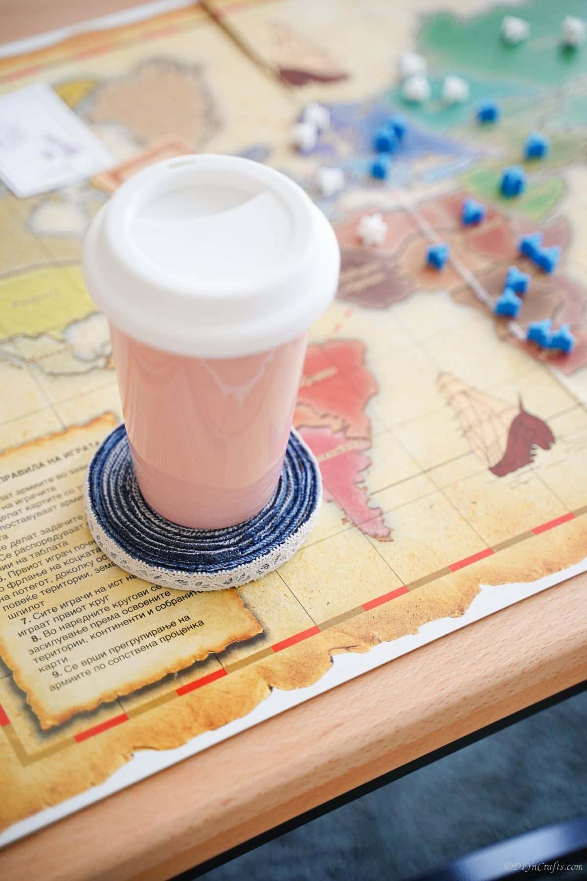 denim coaster under pink coffee mug on map