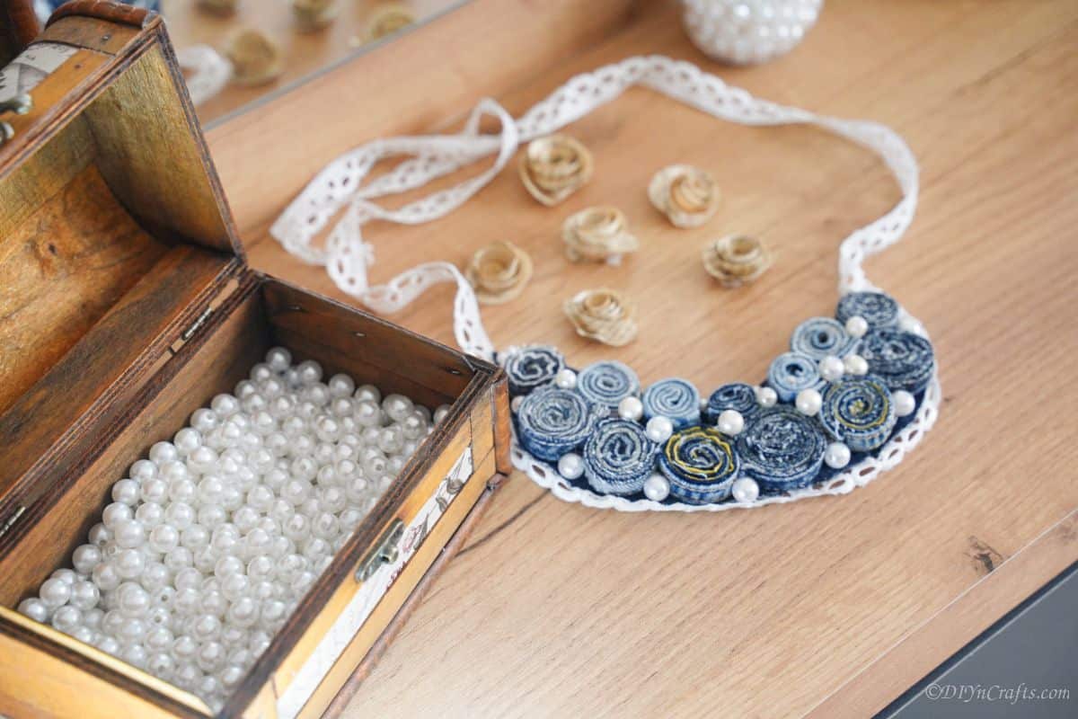 pearls in box next to denim necklace on vanity