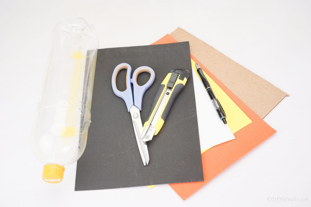 black orange yellow and cardboard paper on white table with scissors