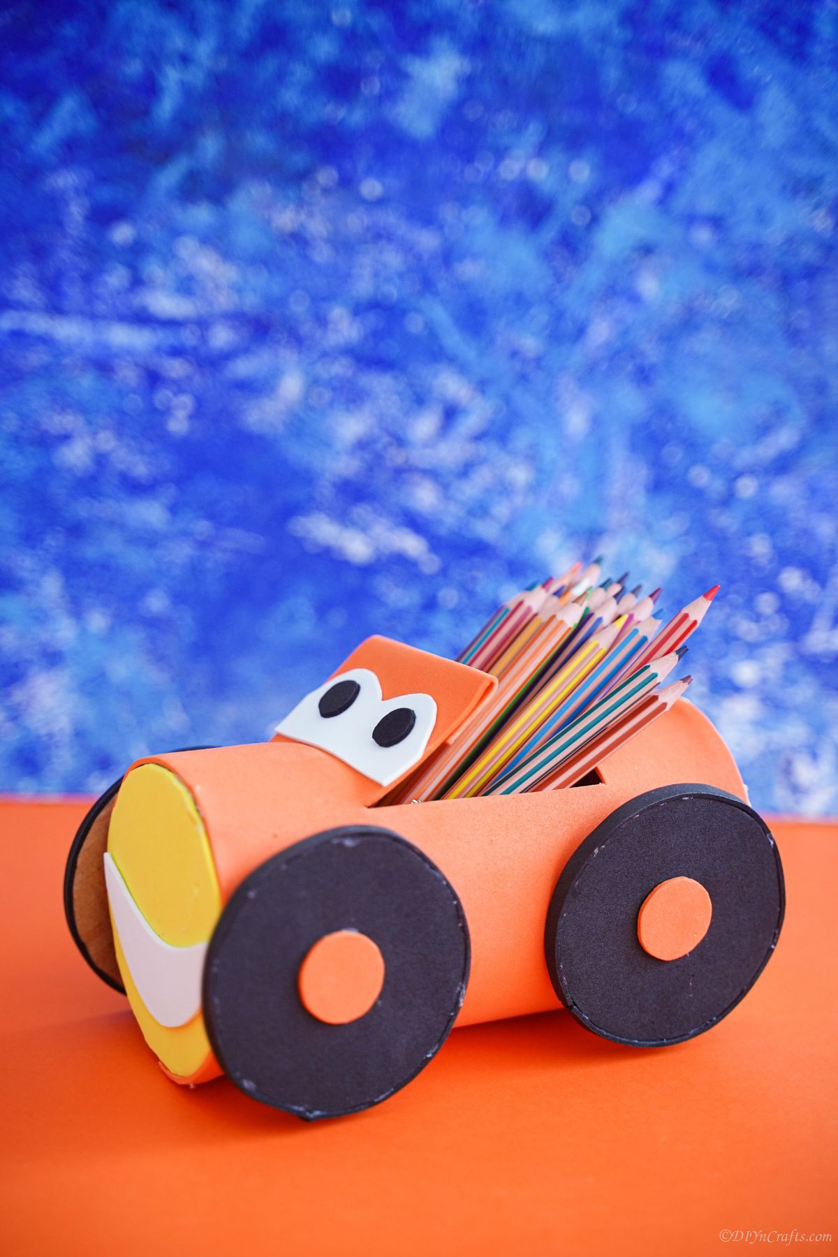 blue background behind orange plastic bottle car pencil holder