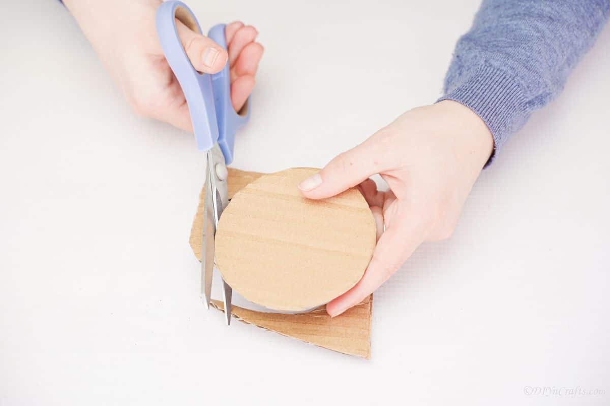blue scissors cutting cardboard circle