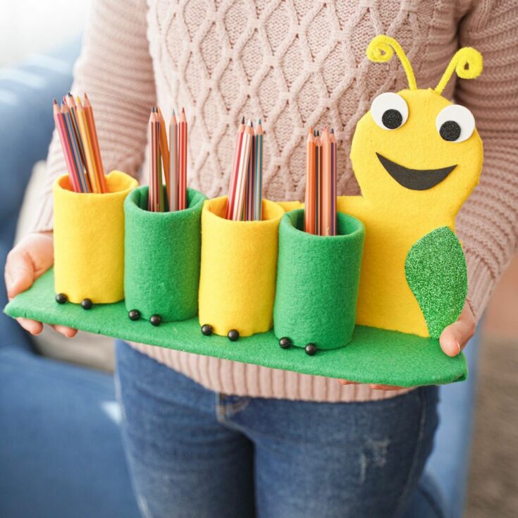 woman in pink sweater holding caterpillar pencil holder