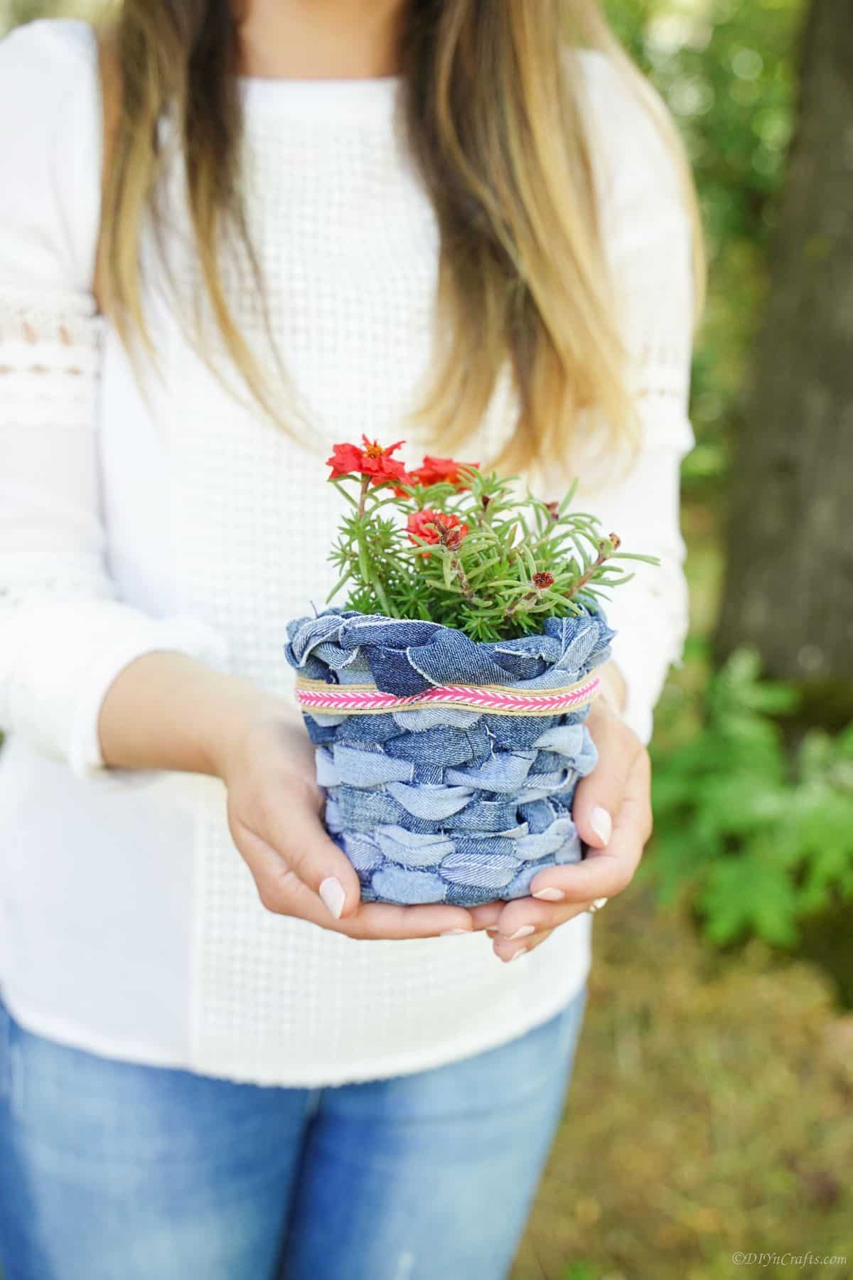 red flowers in blue jeans basket held by woman
