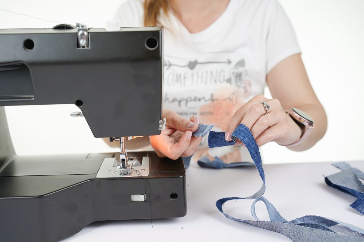 woman at black sewing machine with strips of denim