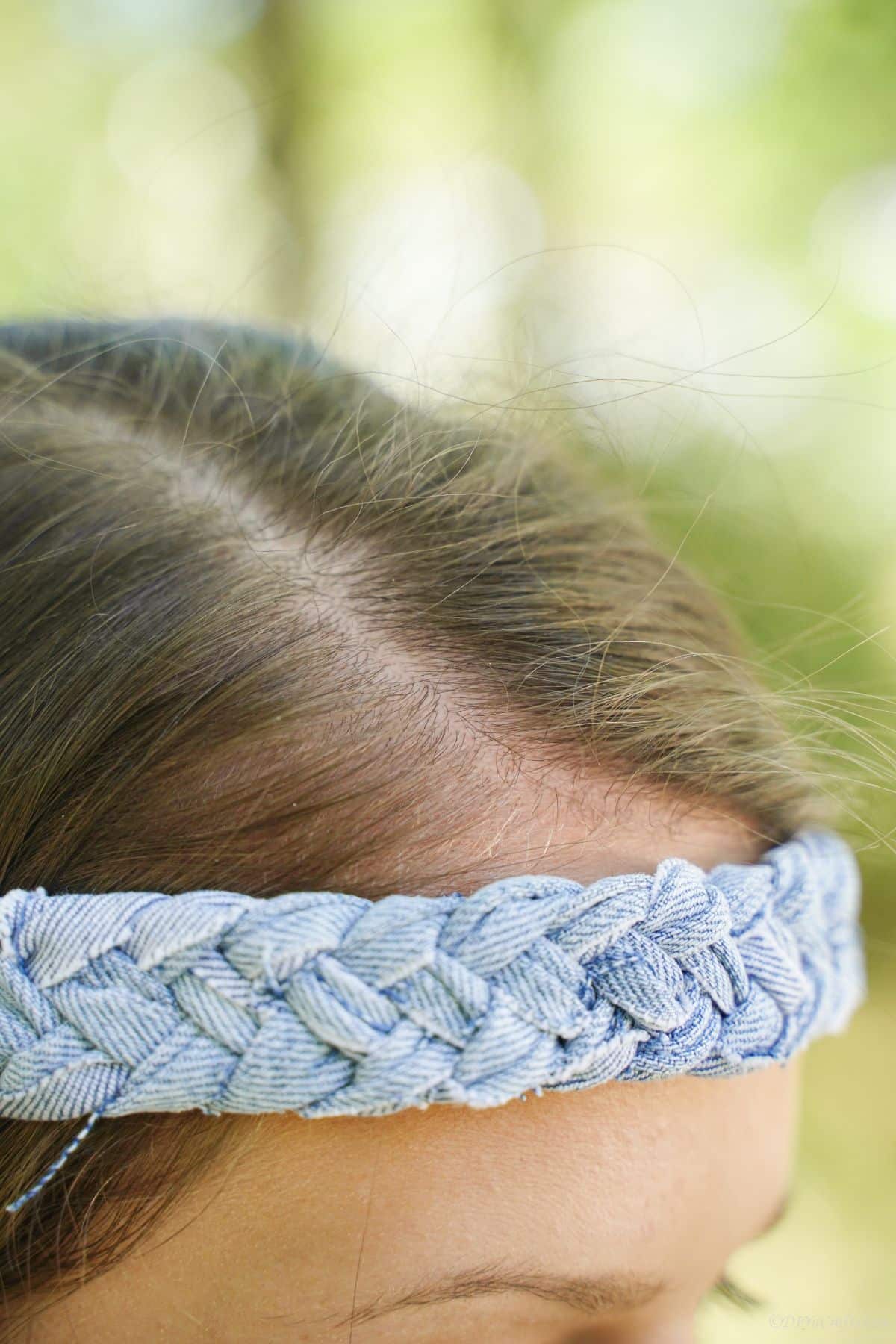 side of denim headband visible on top of brunettes forehead