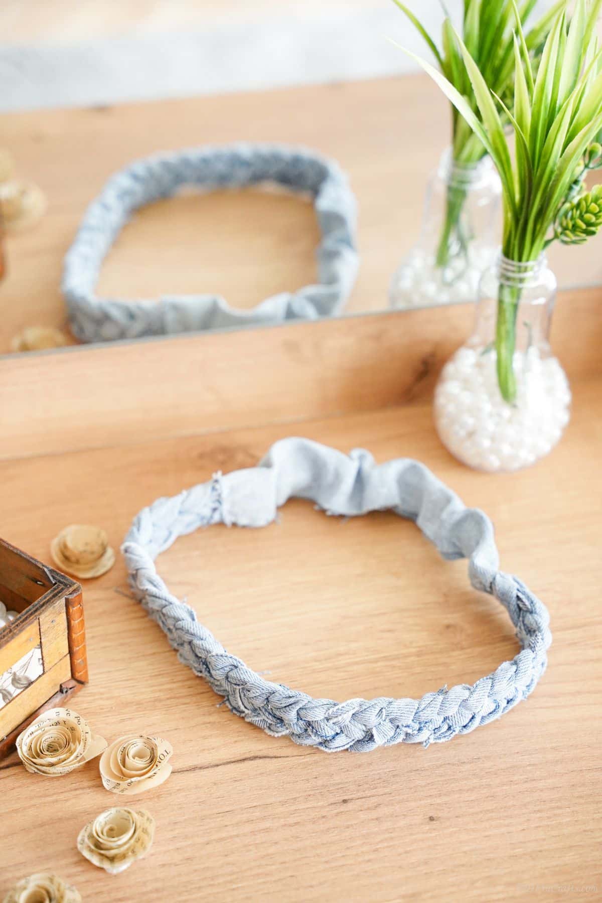 headband made of old blue jeans laying on light wood cabinet with mirror