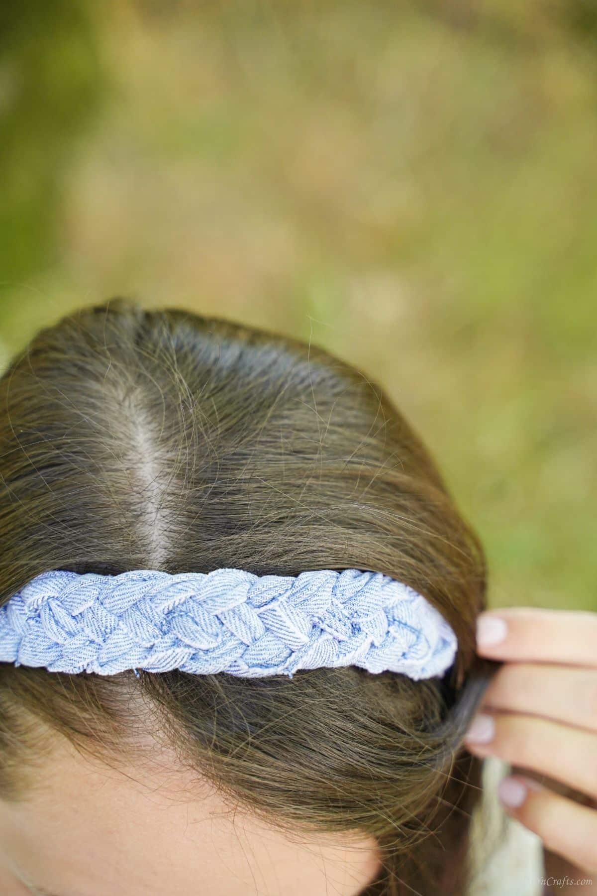 lady holding her hair aside to show denim headband