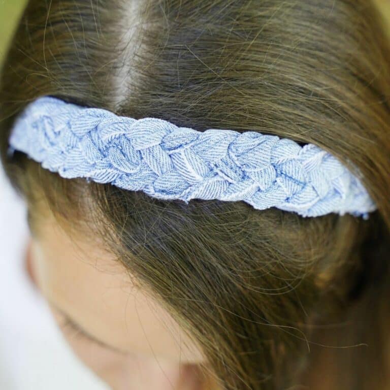 looking down at the top of a braided denim headband being worn by a woman with brown hair