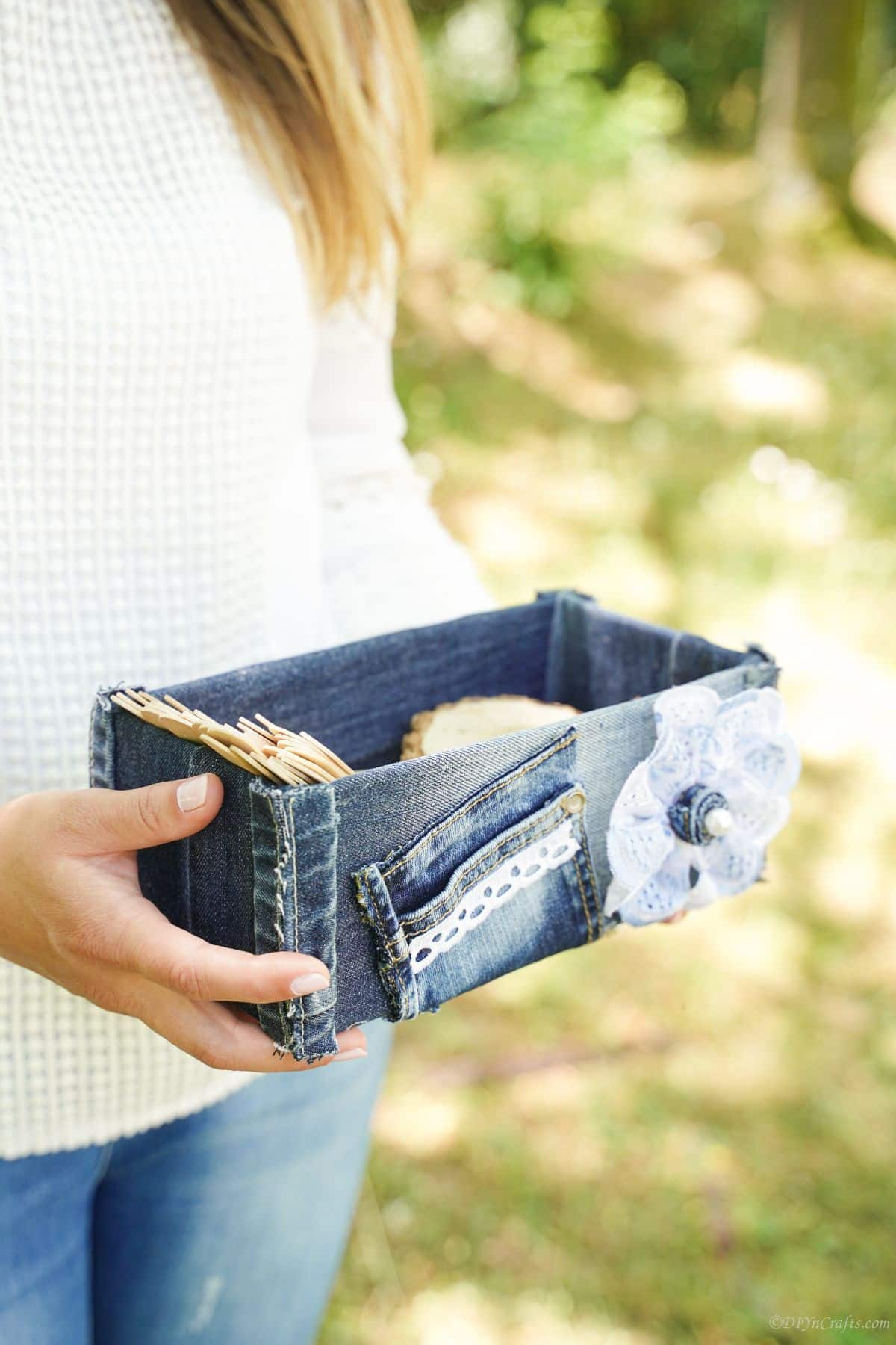 woman in white shirt holding a denim covered box