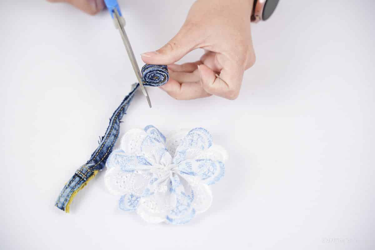 blue scissors cutting seam of denim above white bow