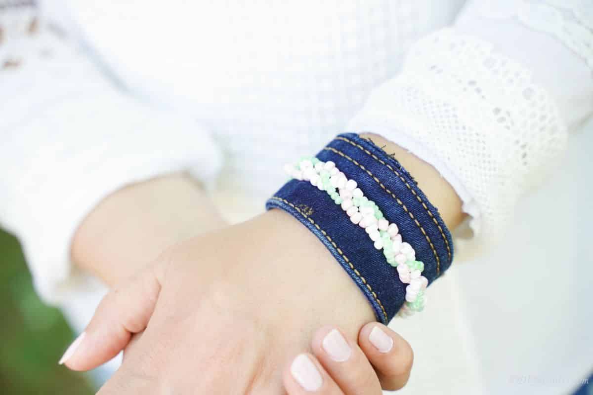 blue jean bracelet with beads on wrist of woman in white shirt