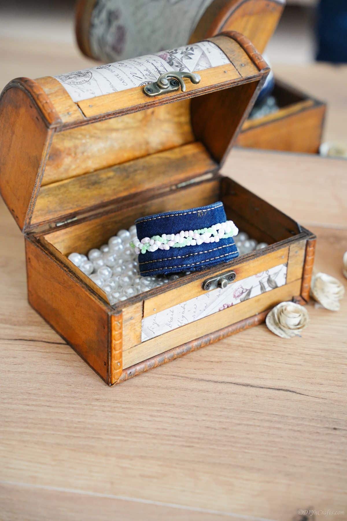 mini wooden chest filled with fake beads and a denim cuff bracelet