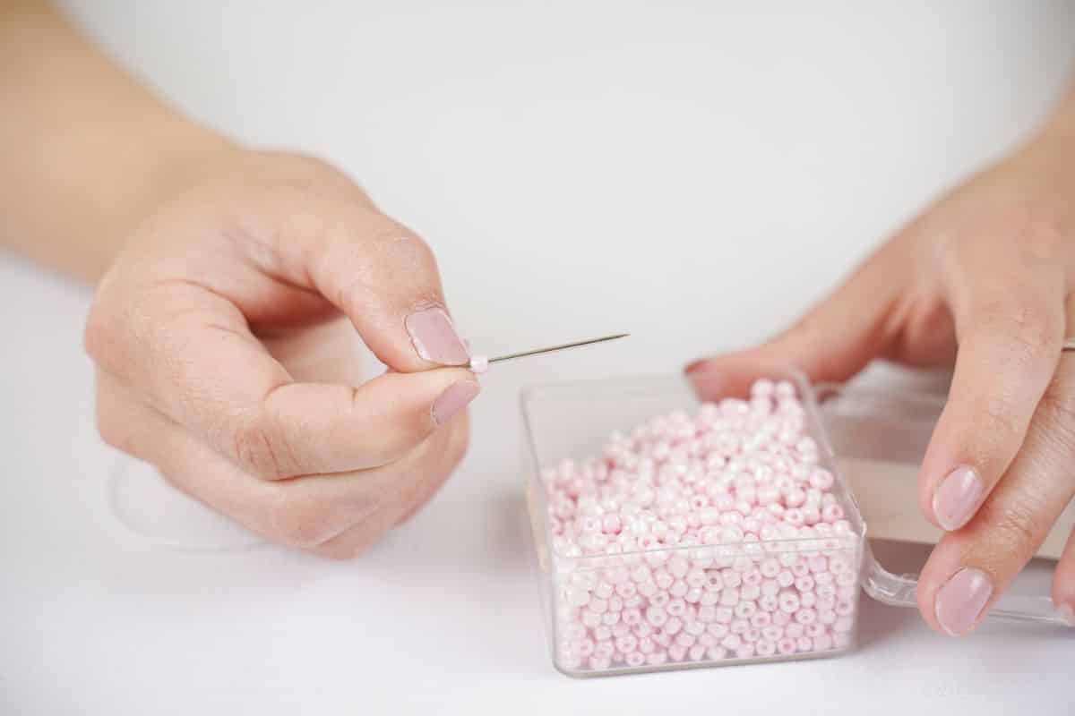 needle adding seed beads to string