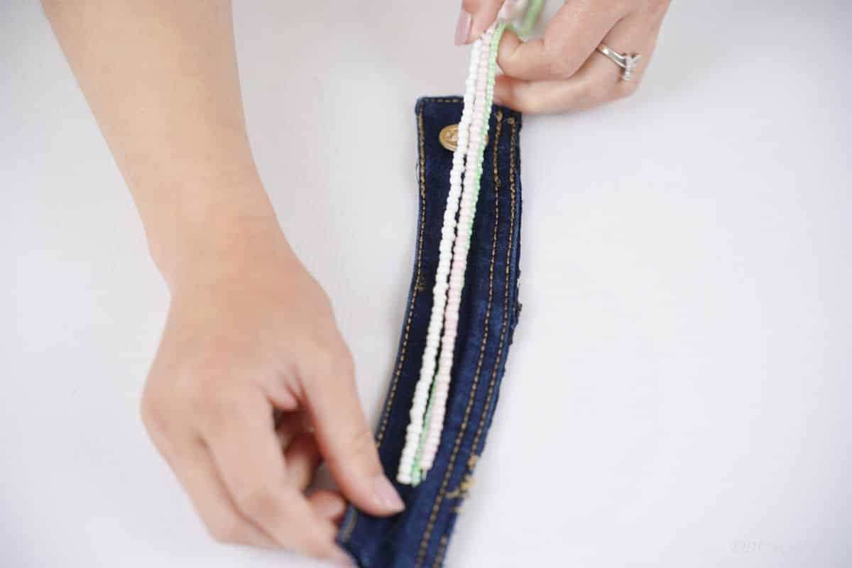 hand securing beads to denim