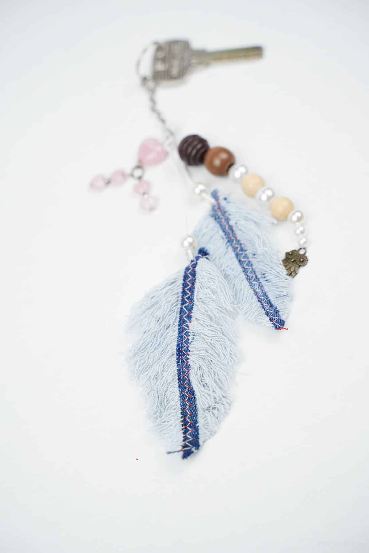 denim feather keychain laying on white table