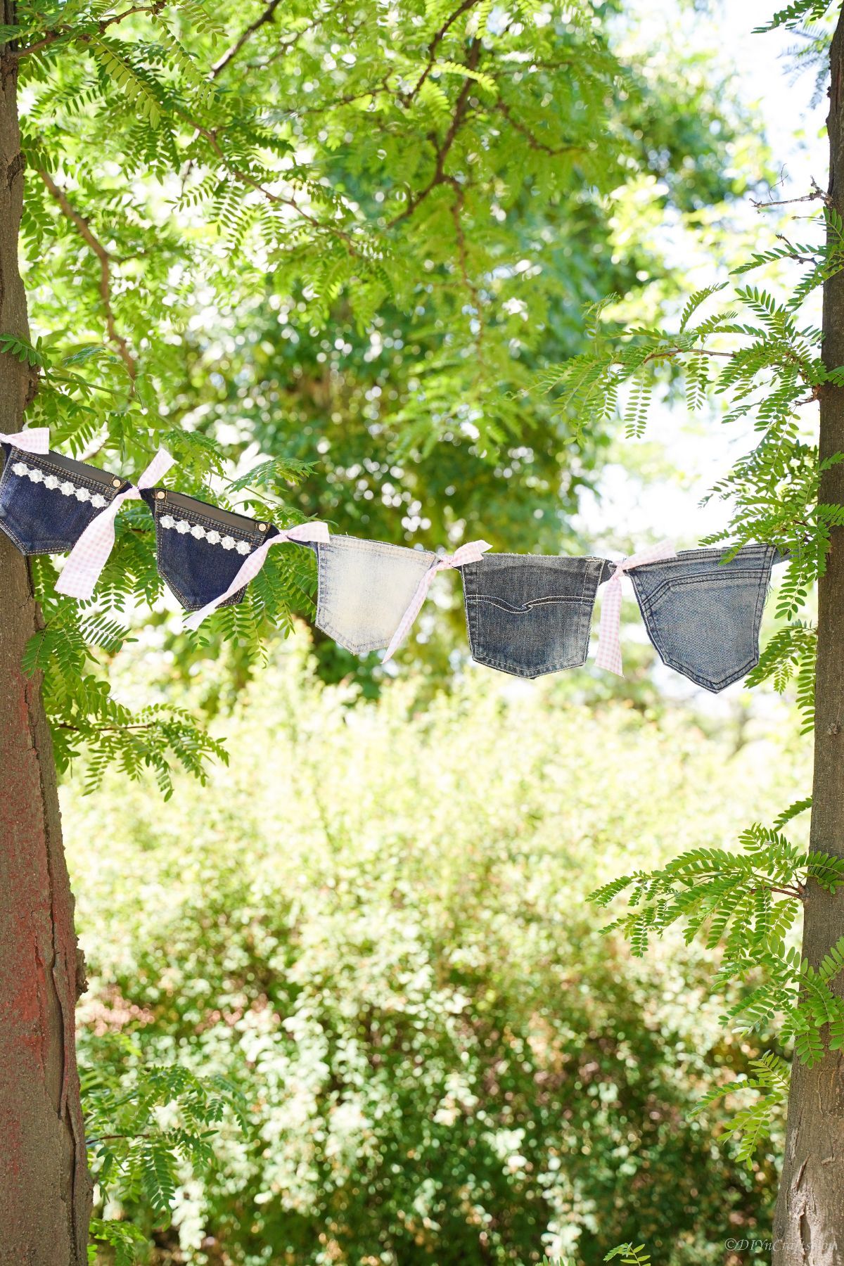 denim garland hanging between two trees outside