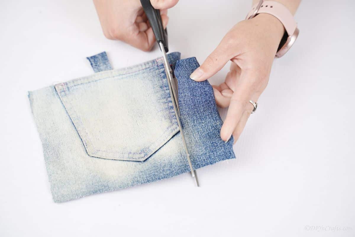 black scissors being used to cut pocket from denim