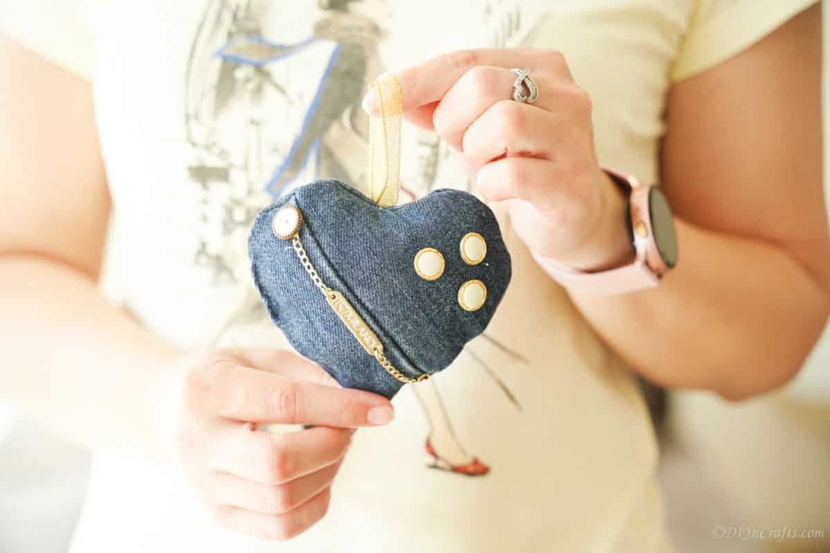 woman holding a denim heart with gold chain and buttons