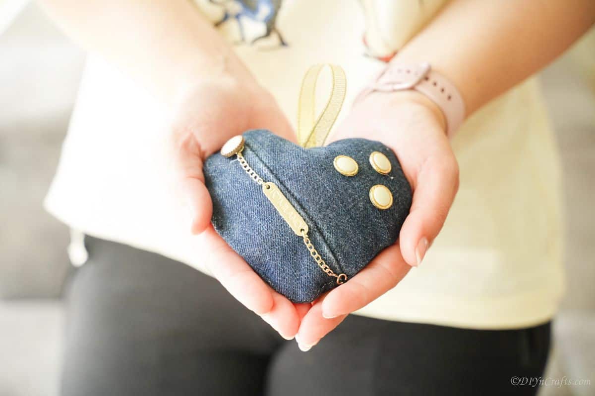 heart sachet with denim cover and gold accents beign held in hands