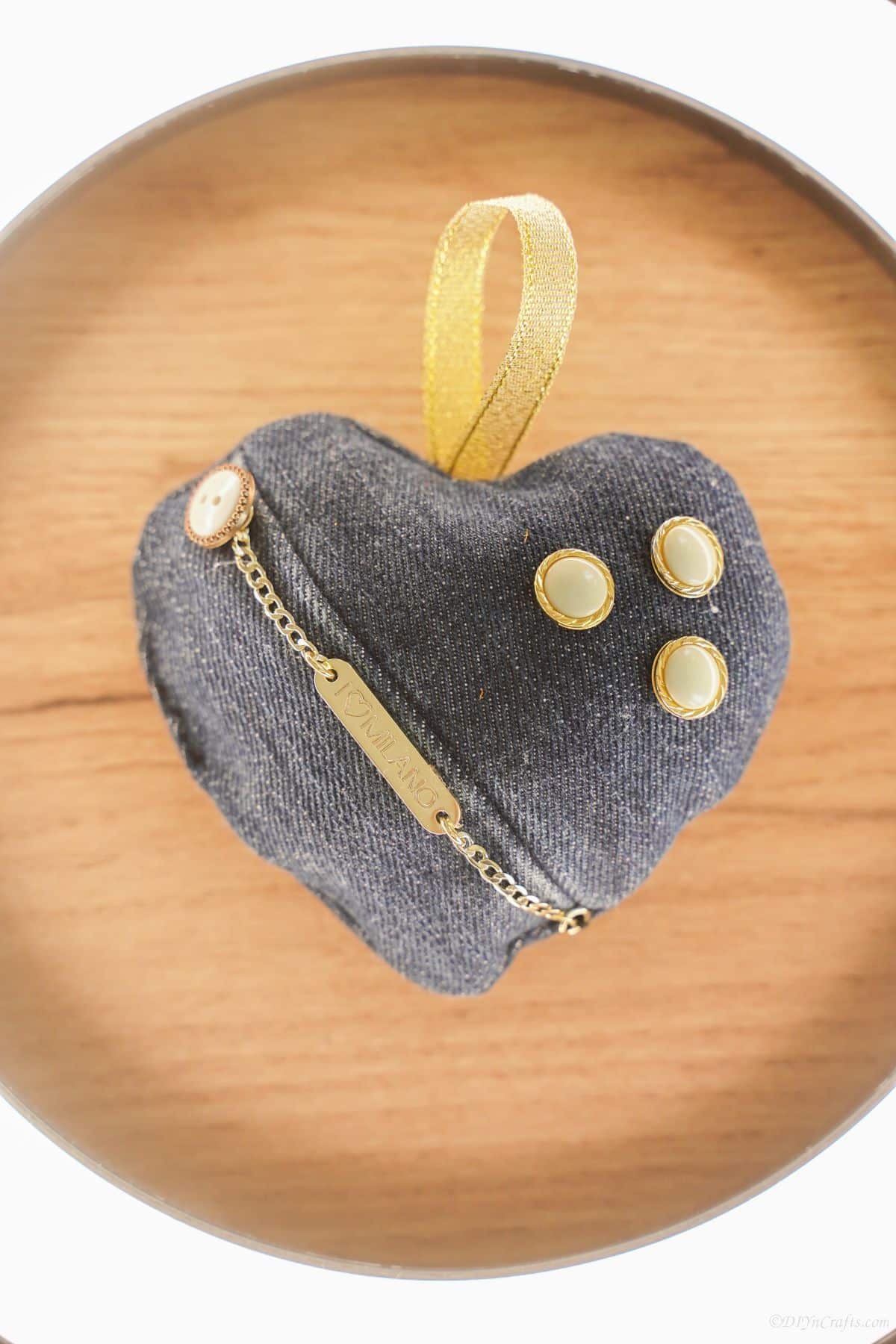 round wood board with denim and gold heart sachet in center