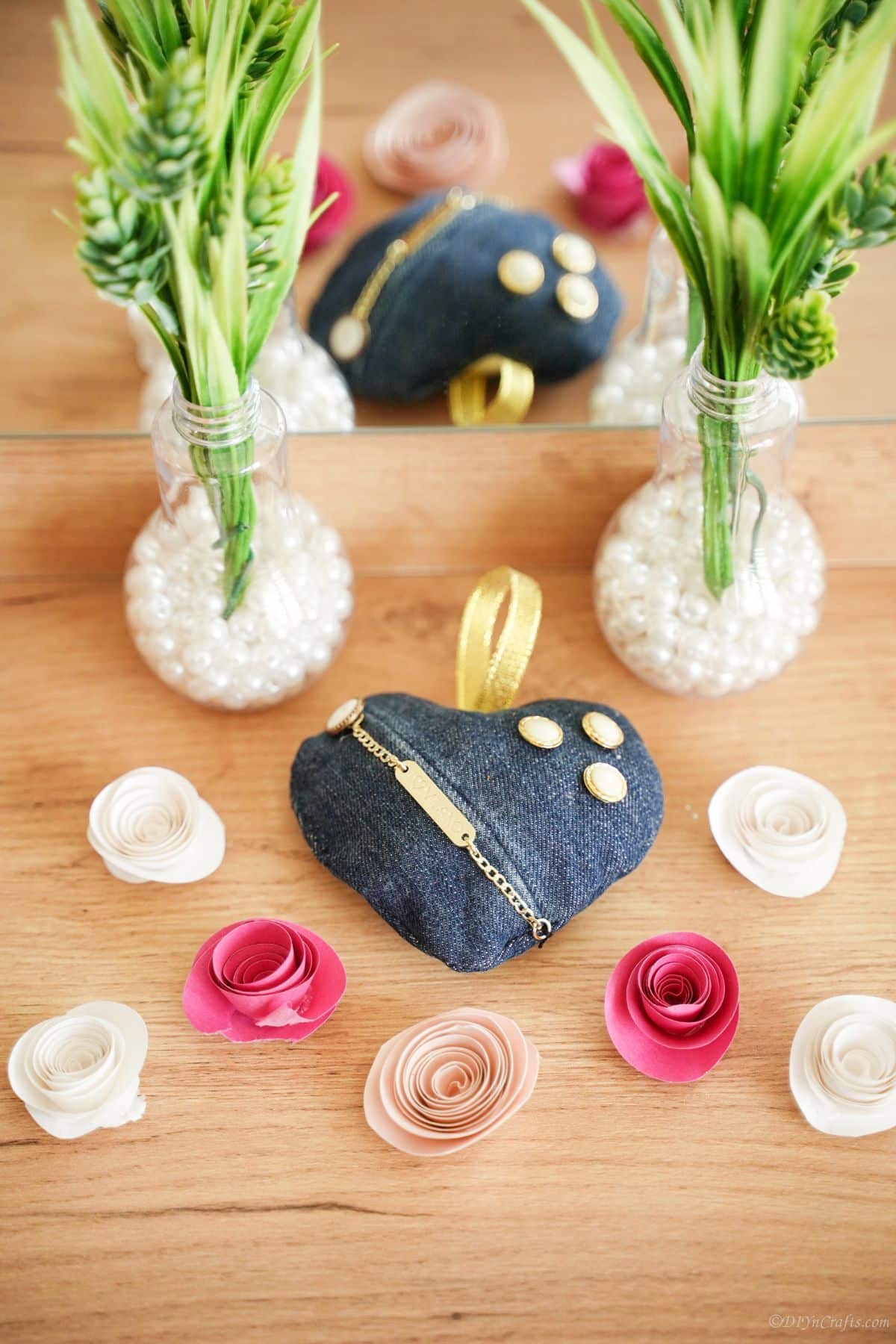 denim heart on table with fake plants and fake pink and white paper flowers