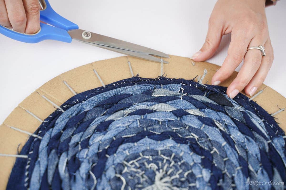 blue scissors snipping yarn on edge of cardboard