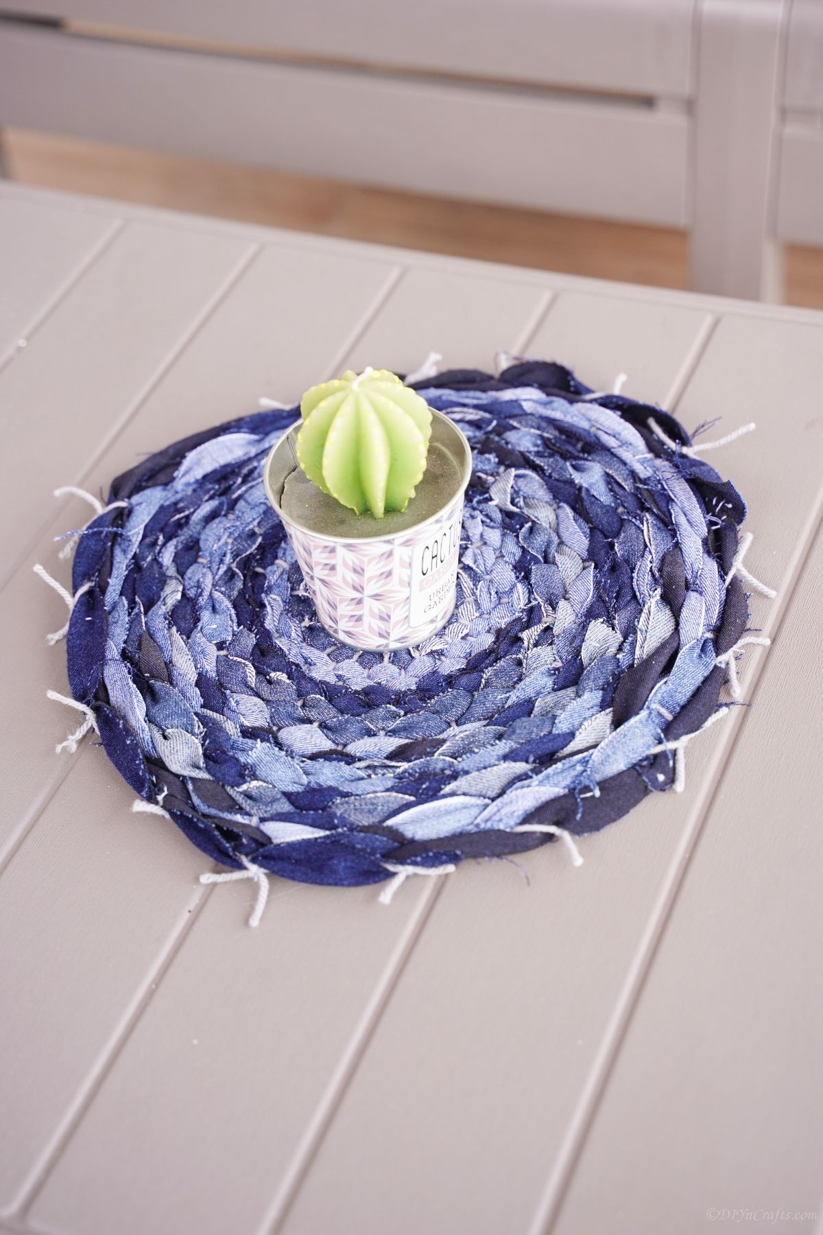 round denim placemat on gray table with cactus plant