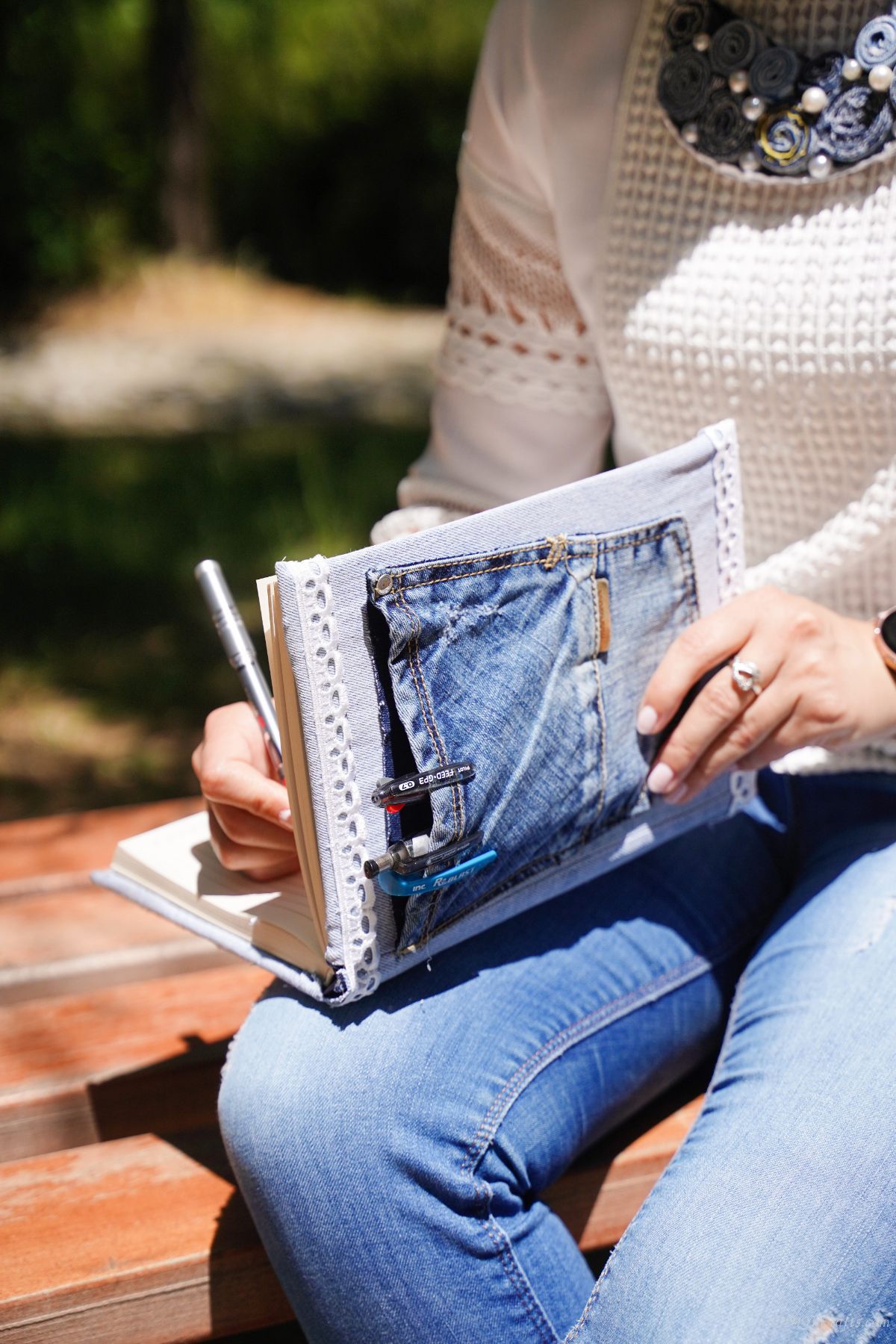 lady in white shirt sitting on picnic table writing in journal