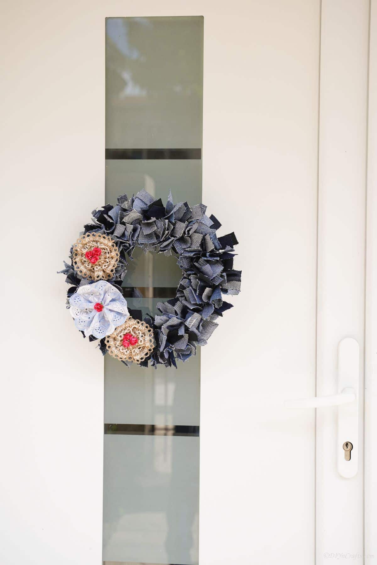 denim and lace wreath hanging on white door with glass panel in center