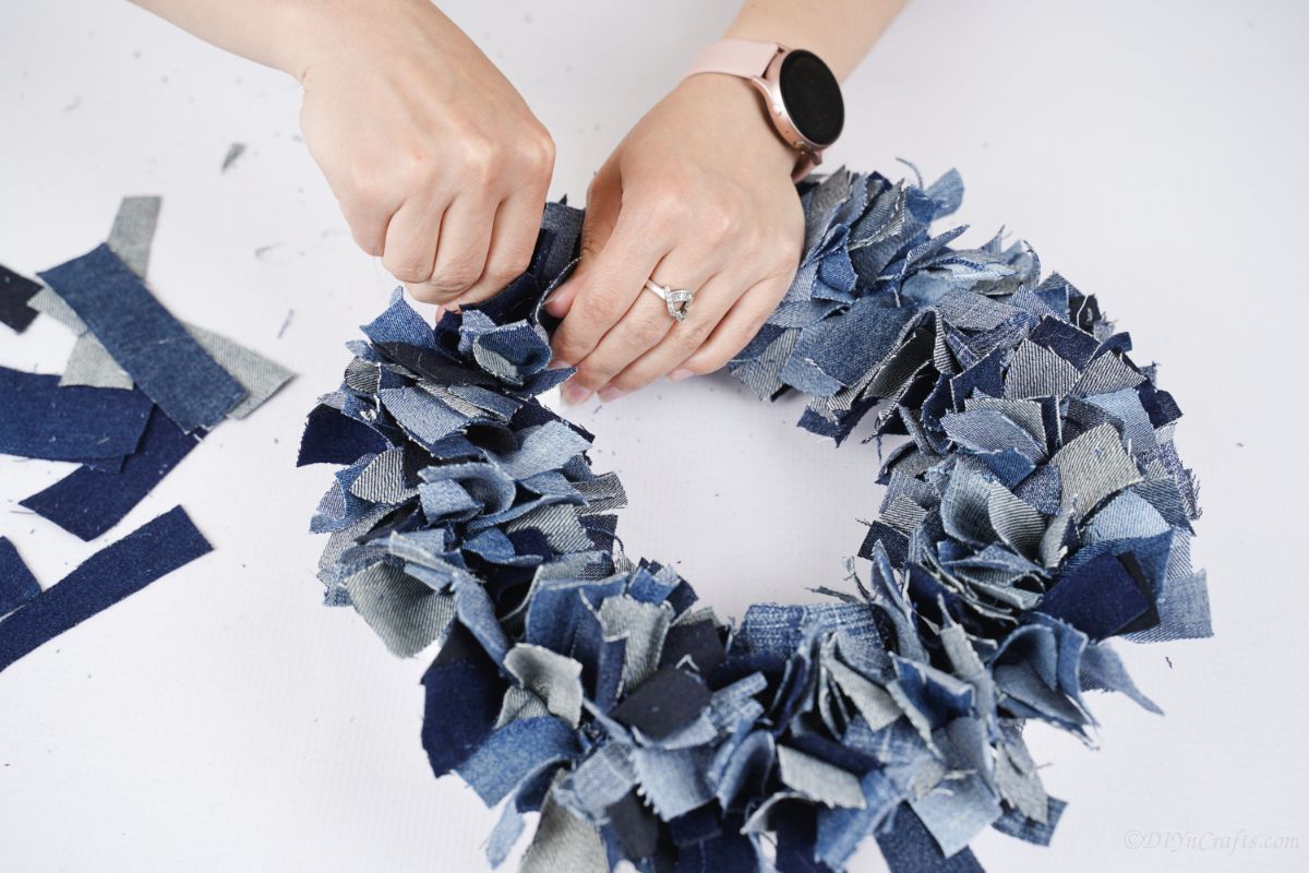 hands pushing the last bit of denim in to cover foam wreath