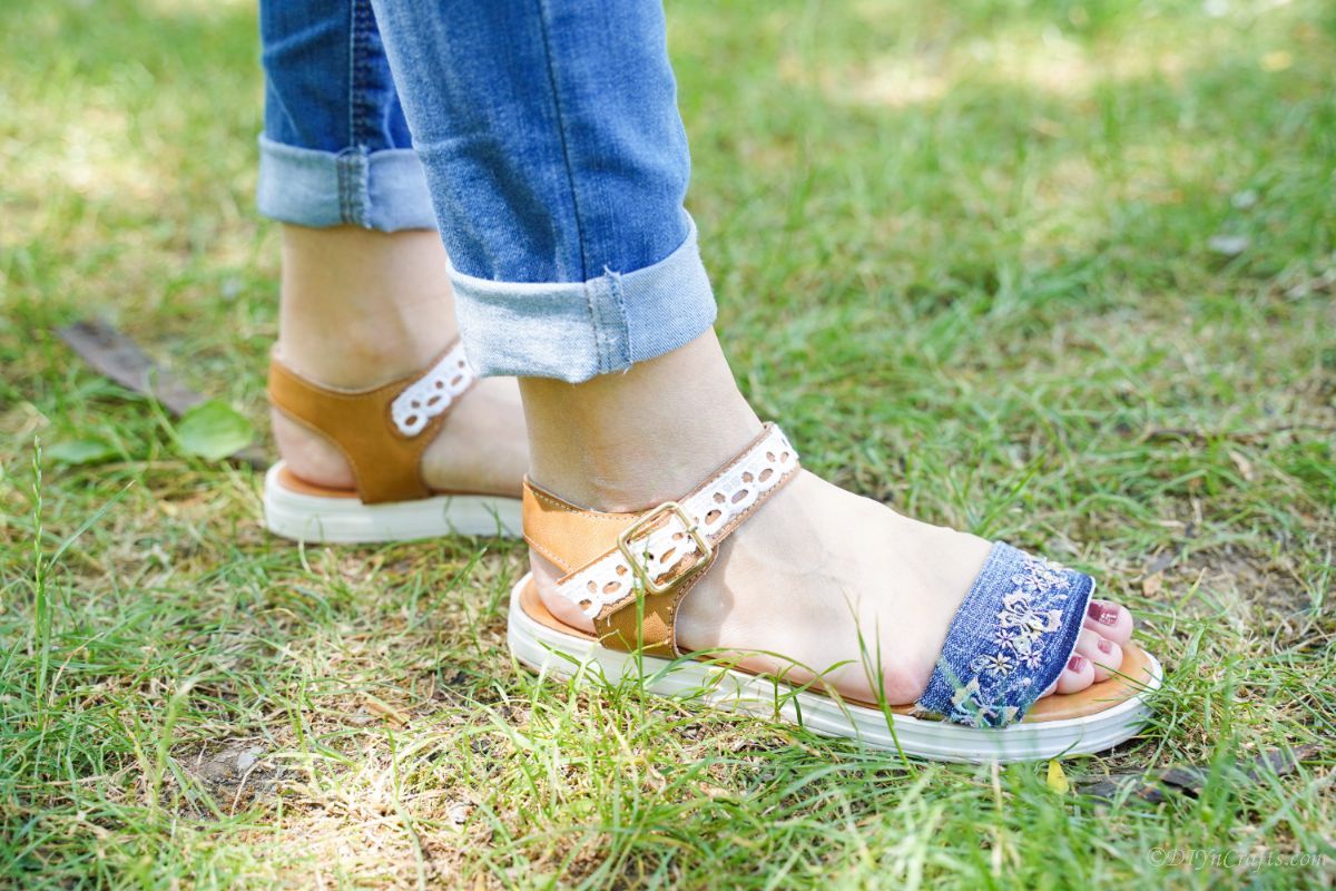 woman in cuffed jeans waering lace and denim sandals outside on grass