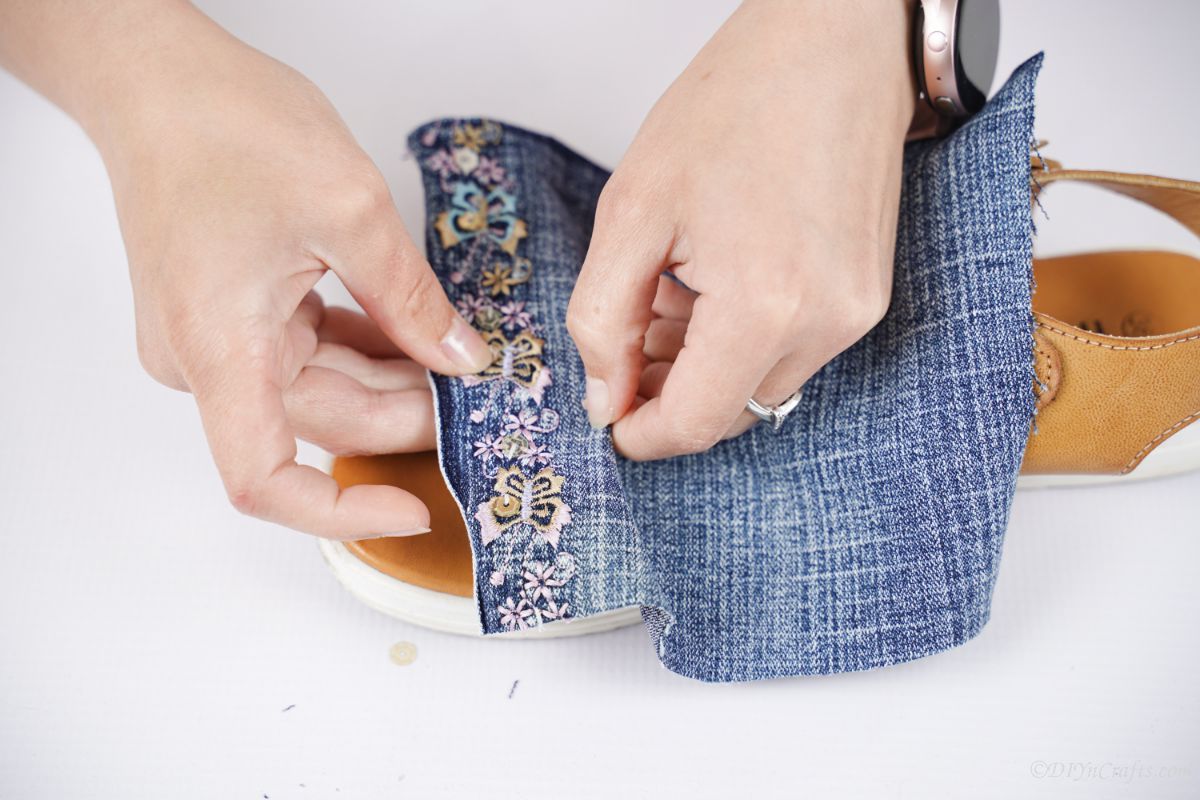 hand putting denim with beads across top of sandals
