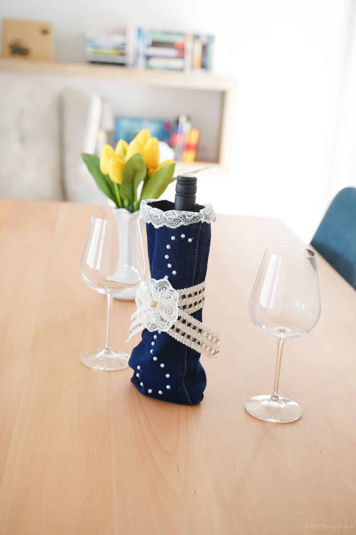 denim wine bottle cover sitting on table with blue chairs