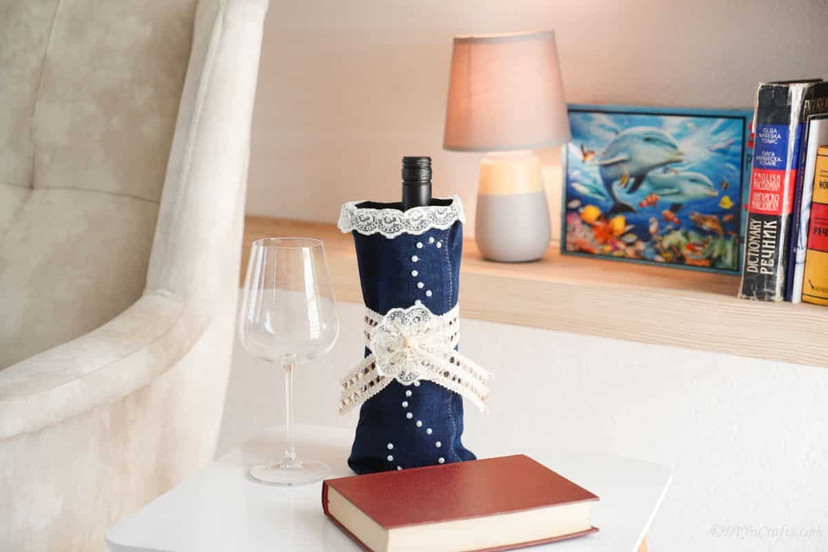 denim wine bottle cover on table by brown book