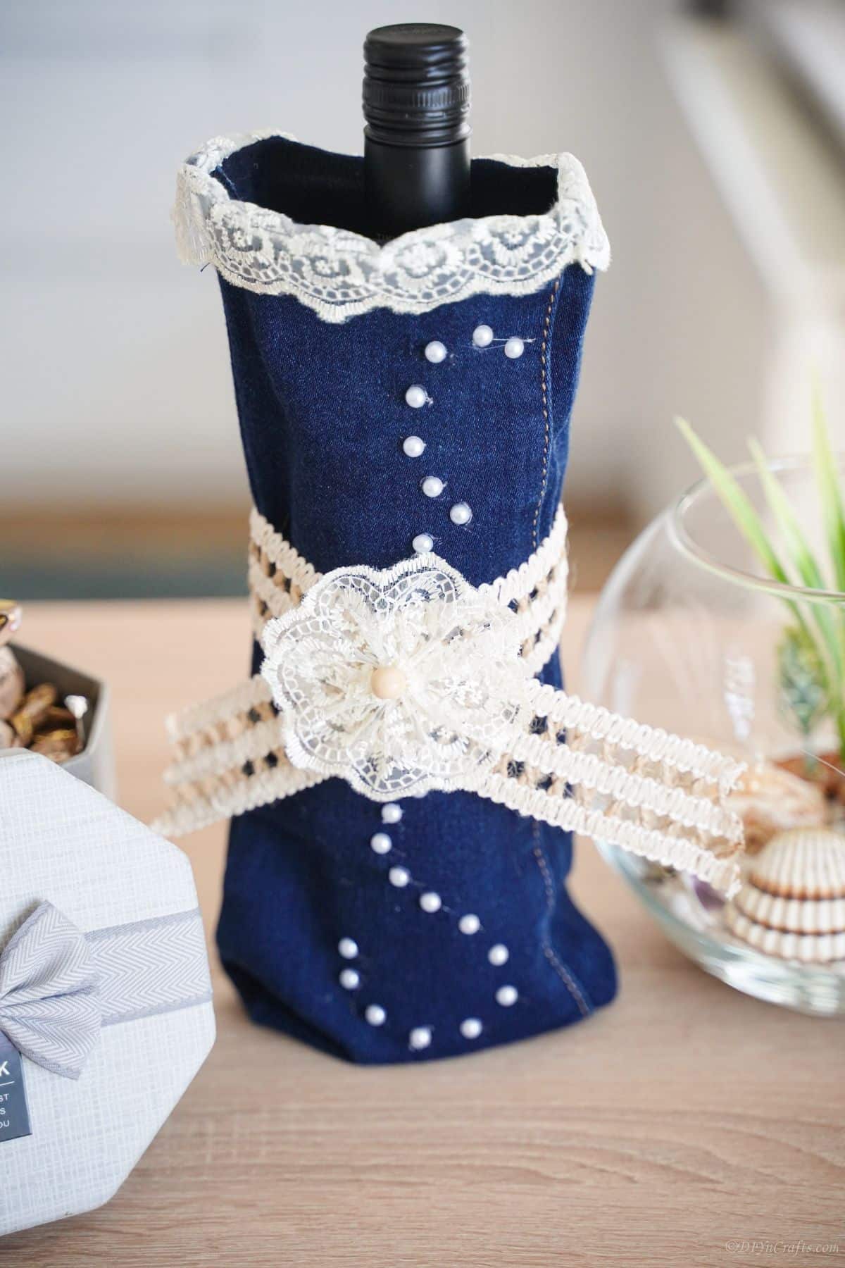 denim and lace wine bottle cover on light wood table
