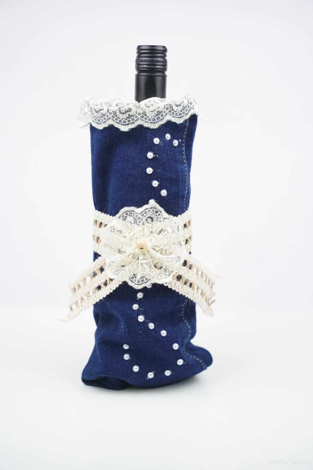 denim and lace wine bottle cover against white wall